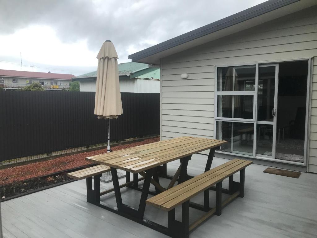 a wooden picnic table and an umbrella on a patio at Westport Central Apartment in Westport
