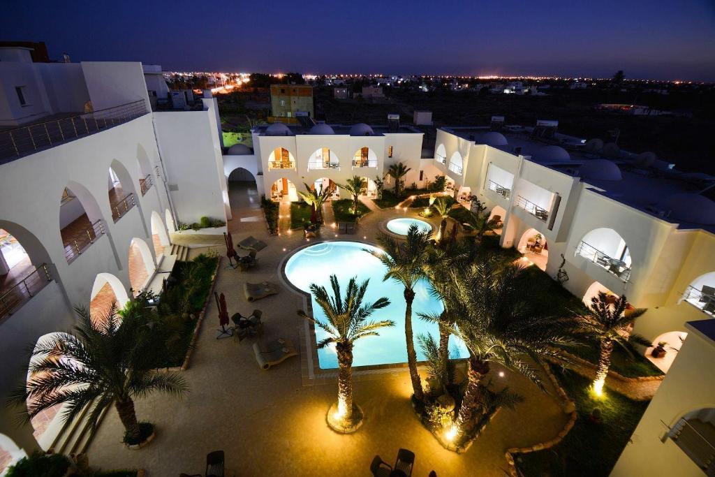 an aerial view of a building with a pool and palm trees at Palm Djerba Suites in Mezraya