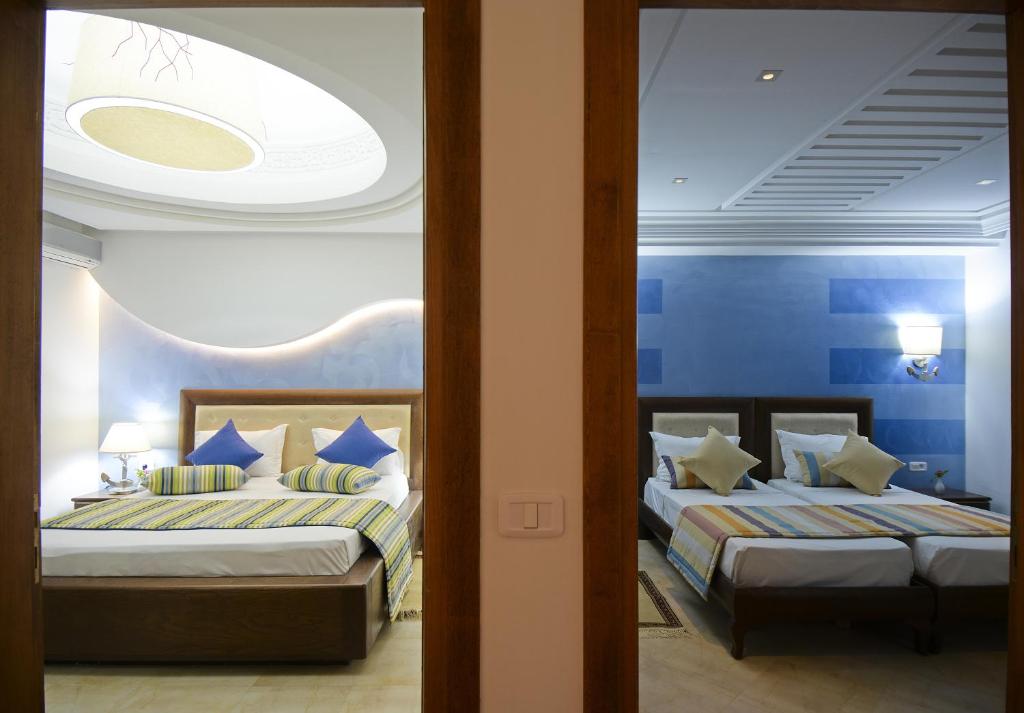 two beds in a bedroom with blue walls at Palm Djerba Suites in Mezraya
