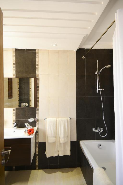 a bathroom with a bath tub and a sink at Palm Djerba Suites in Mezraya