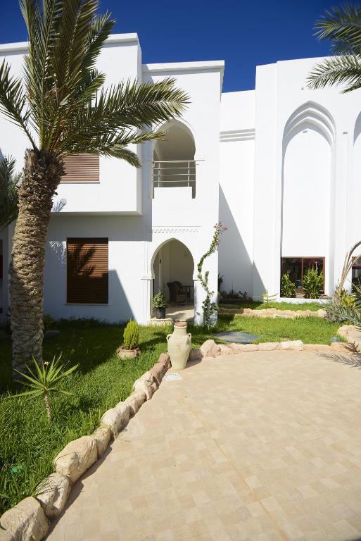 a palm tree in front of a white house at Palm Djerba Suites in Mezraya