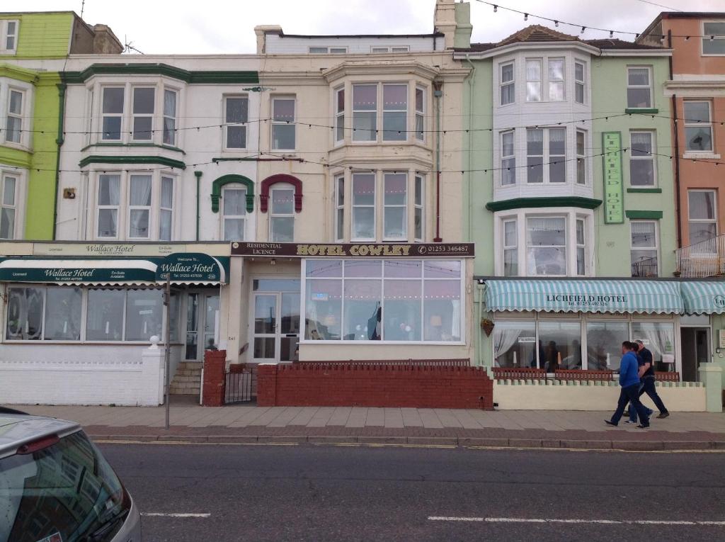 2 personnes marchant dans la rue devant un bâtiment dans l'établissement Cowley Hotel, à Blackpool