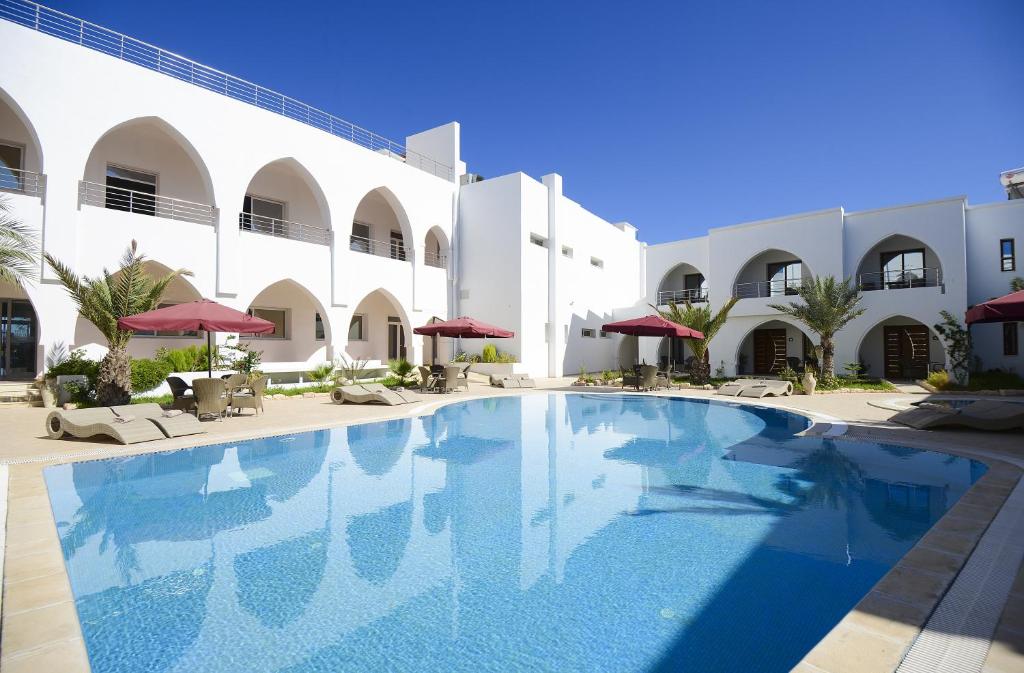 a swimming pool in front of a building at Palm Djerba Suites in Mezraya