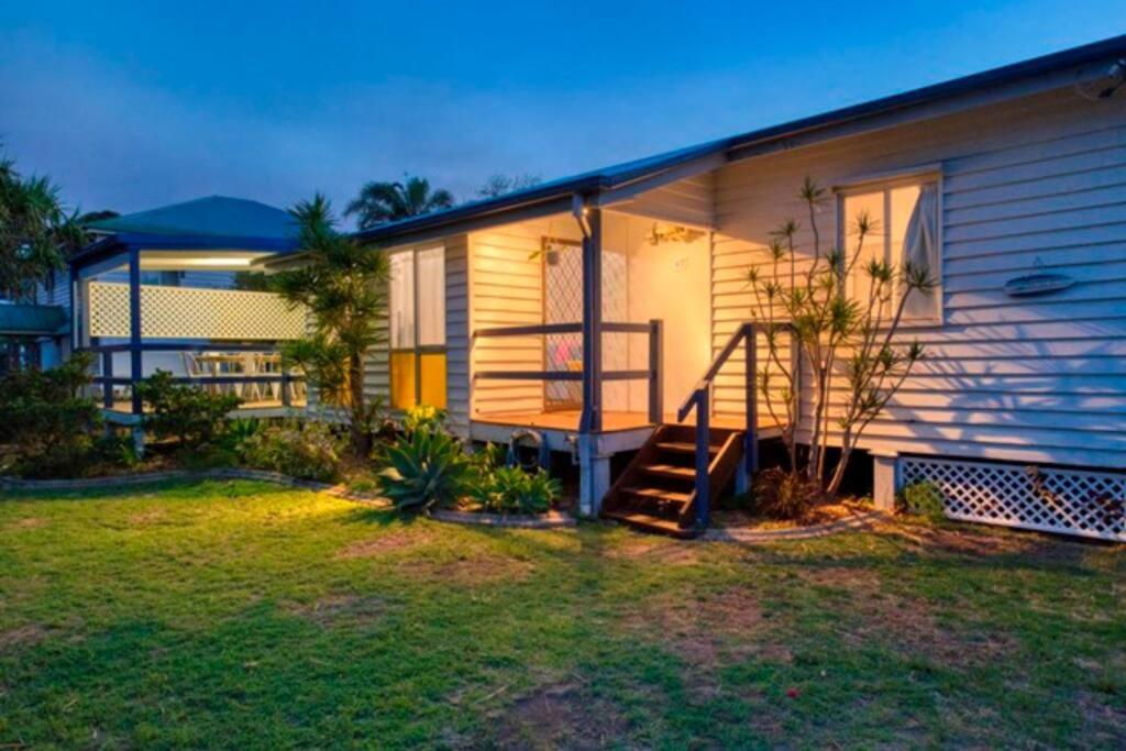 a house with a staircase next to a yard at Sandy Feet Cottage in Bargara