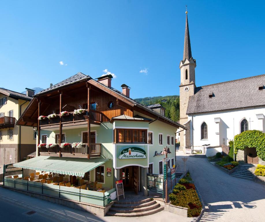 ein großes Gebäude mit einer Kirche mit einem Kirchturm in der Unterkunft Mesnerhaus Mühlbach in Mühlbach am Hochkönig