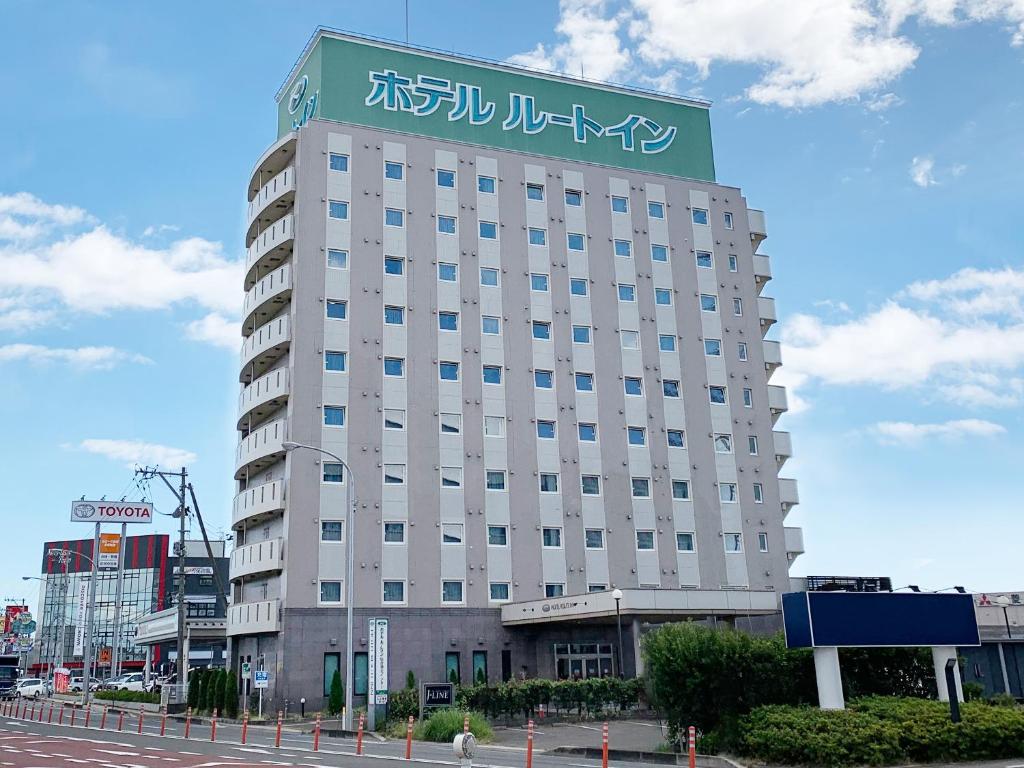 un gran edificio con un cartel encima en Hotel Route-Inn Sendaiko Kita Inter en Tagajo