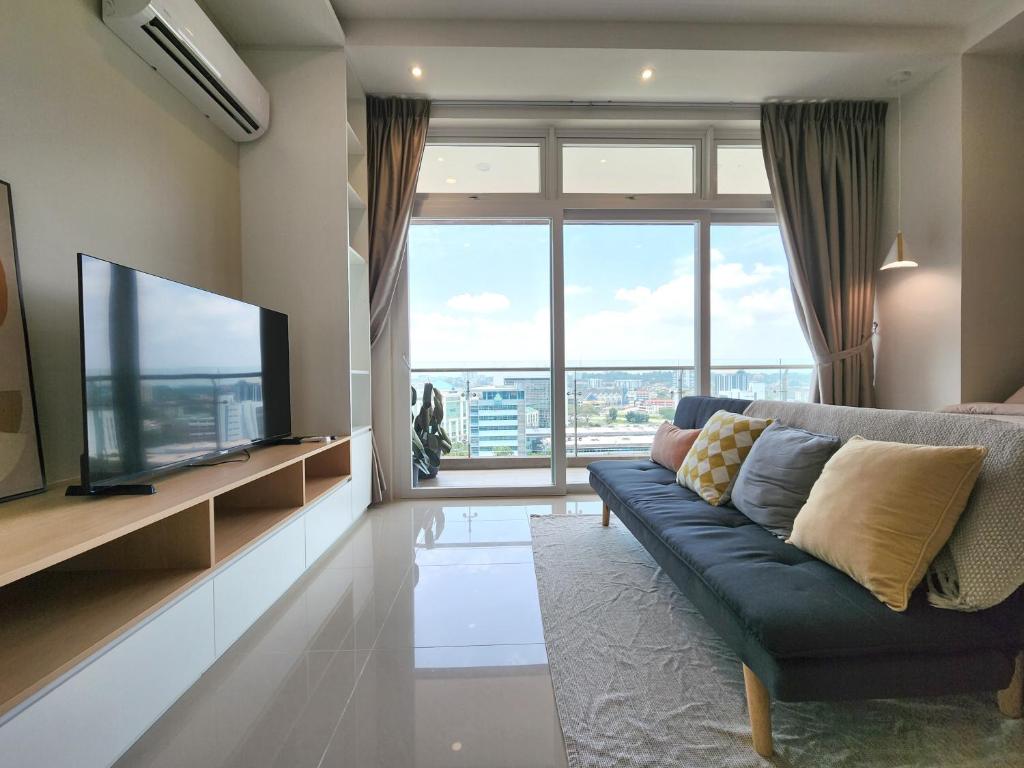 a living room with a blue couch and a large window at Kuching Town DeSunset - Balcony with Amazing View in Kuching