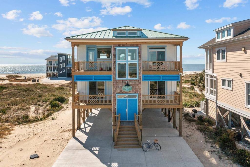 a house on the beach with a blue door at SeaSons at the Point in Oak Island