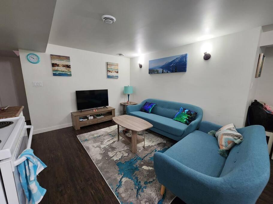 uma sala de estar com um sofá azul e uma televisão em TheAuroras: Vibrant&Cheerful 2 bdrm Stylish suite em Saskatoon