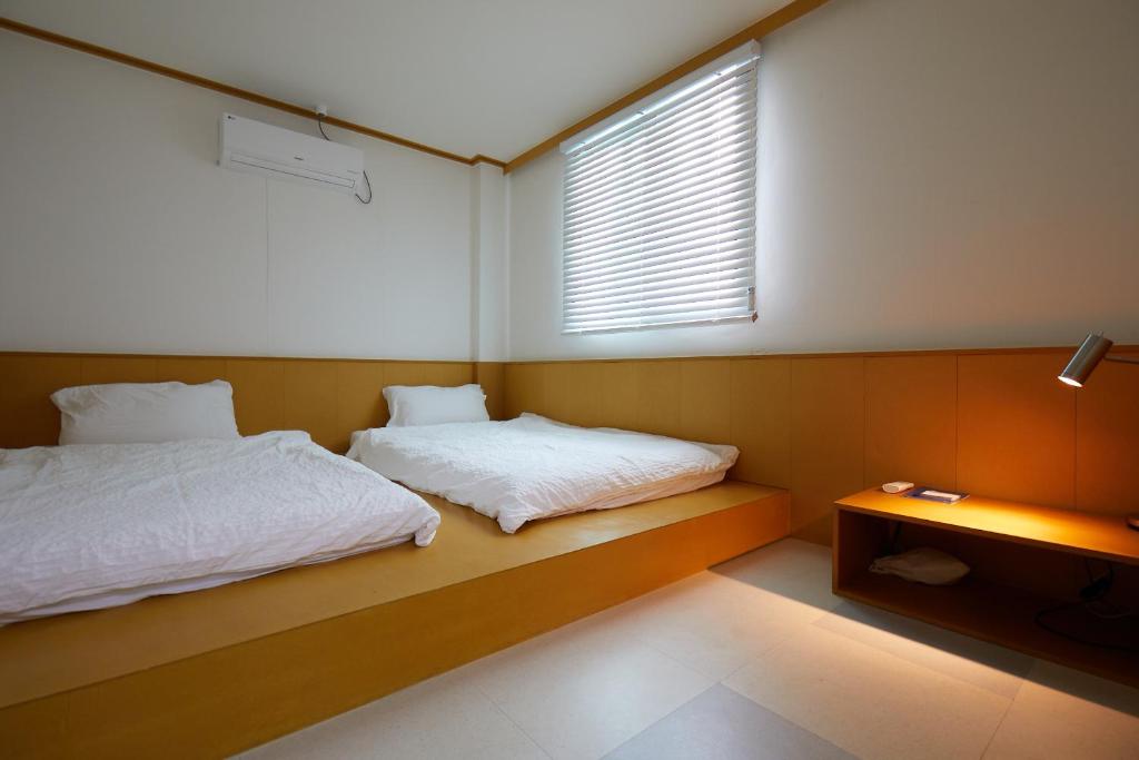 a bedroom with two beds and a window at SloCruise in Gongju