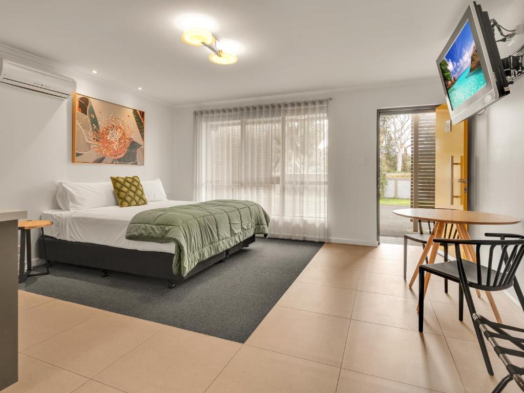 een slaapkamer met een bed en een televisie en een tafel bij BIG4 Ingenia Holidays Queenscliff Beacon in Queenscliff