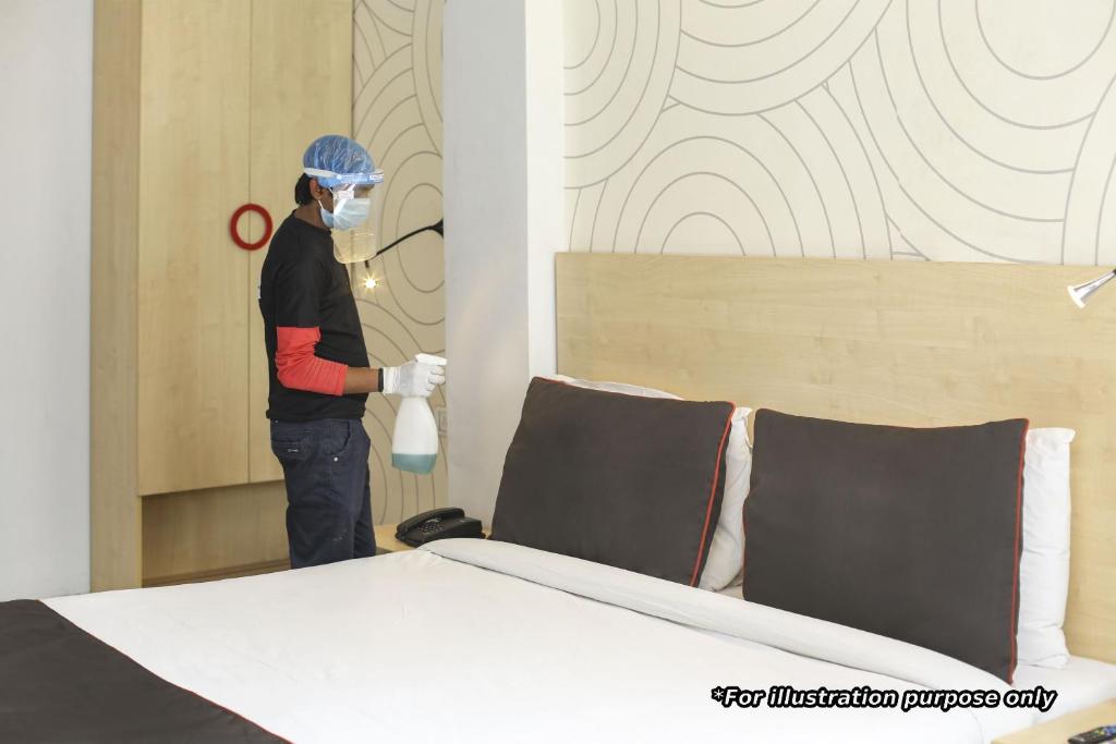 un hombre en una habitación con una máscara y una cama en Townhouse Hotel Refresh en Calcuta
