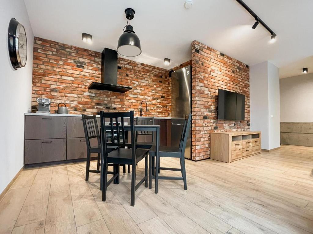 une cuisine avec une table et des chaises ainsi qu'un mur en briques dans l'établissement Urban Apartment Deluxe Szczecin Dąbie, à Szczecin