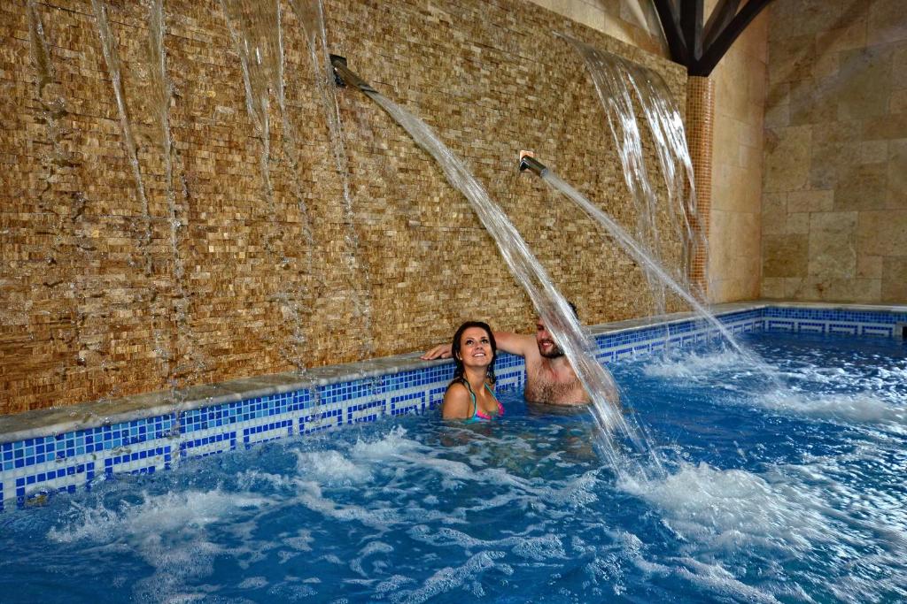 two women in a swimming pool with a waterfall at Hotel Supraśl in Supraśl