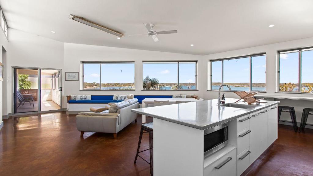 a kitchen and living room with white walls and windows at Walshys Shack in Coffin Bay
