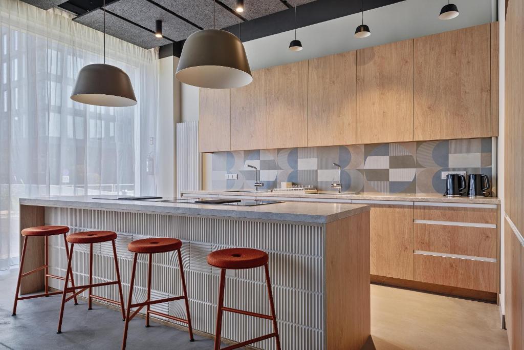 a kitchen with wooden cabinets and stools at a counter at Noli Mokotow in Warsaw