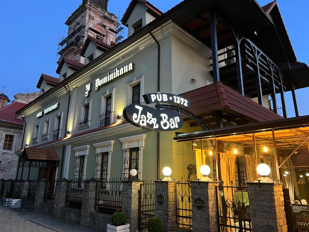 a large white building with a sign in front of it at U Dominicana in Kamianets-Podilskyi