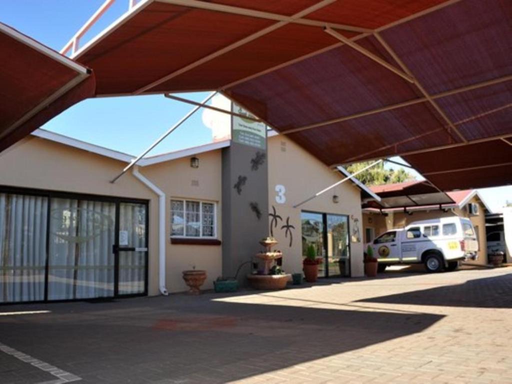 a building with awnings and a car parked in a parking lot at Agros Guest House in Kimberley