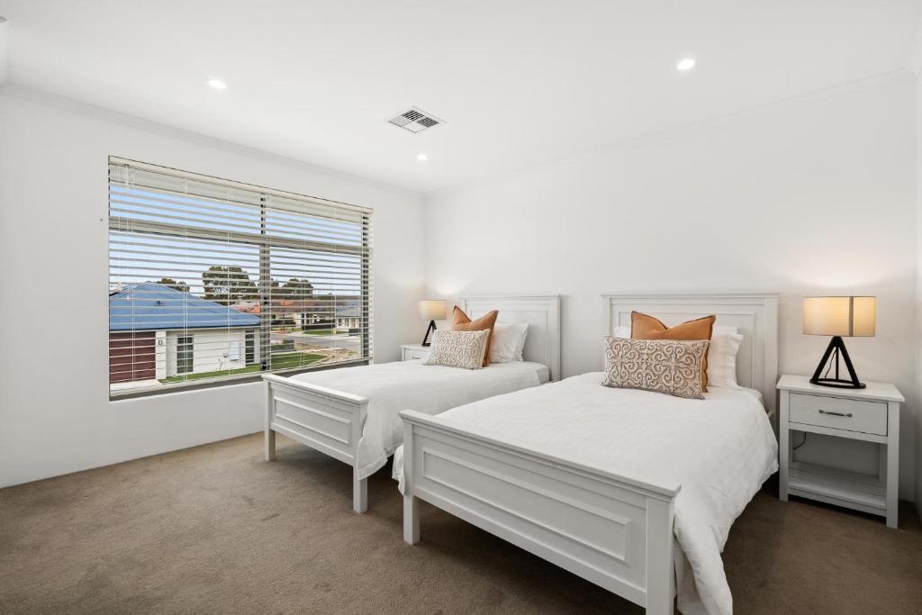 2 camas en un dormitorio blanco con ventana en Modern Minimalistic Home en Perth