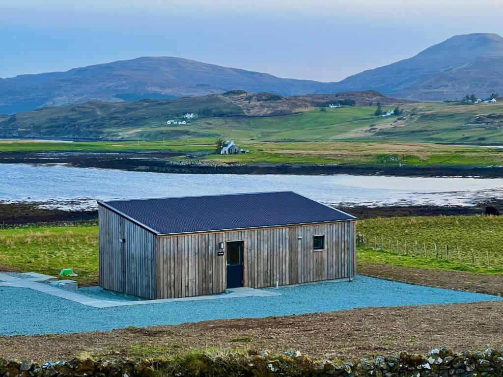 a wooden shed in a field with mountains in the background at The Bothy, Vatten, Dunvegan in Lonmore