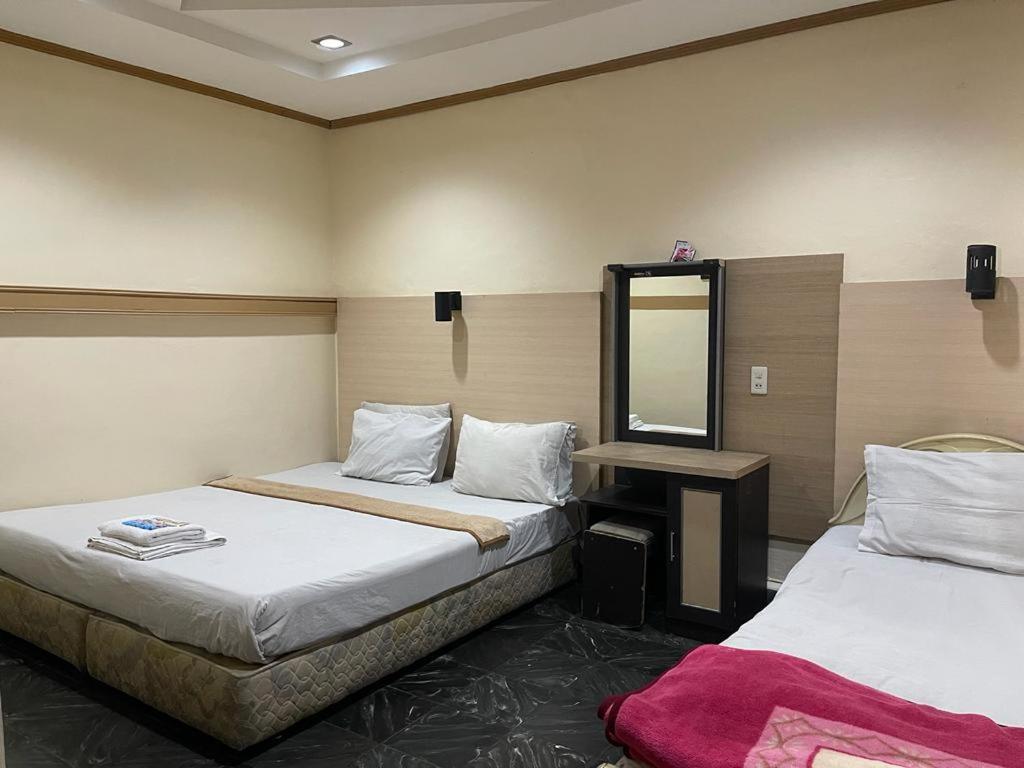una camera d'albergo con due letti e uno specchio di Losmen Sibayak Berastagi a Berastagi