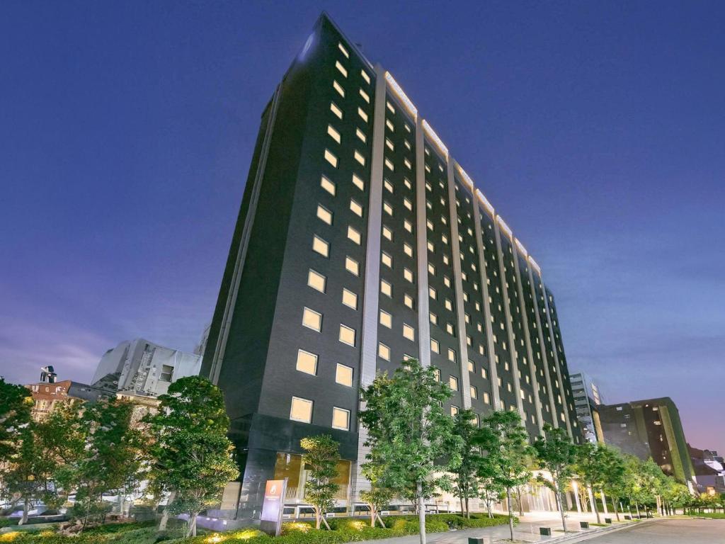 a tall green building with trees in front of it at Hotel Brighton City Osaka Kitahama in Osaka