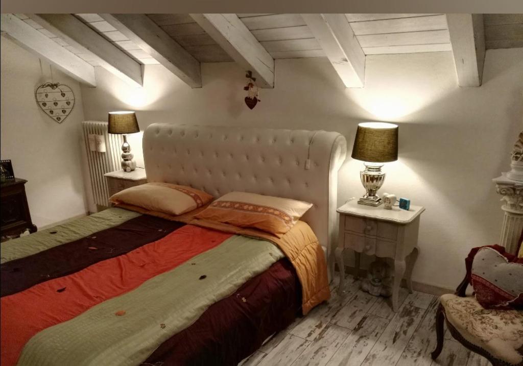 1 dormitorio con 1 cama grande, 2 lámparas y 1 silla en Casa relax, en Aosta