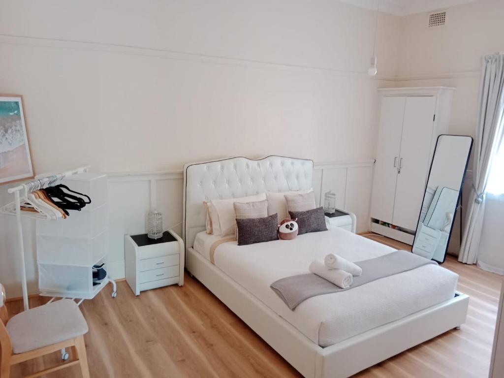 a bedroom with a white bed with a teddy bear on it at Coogee Sunrise in Sydney