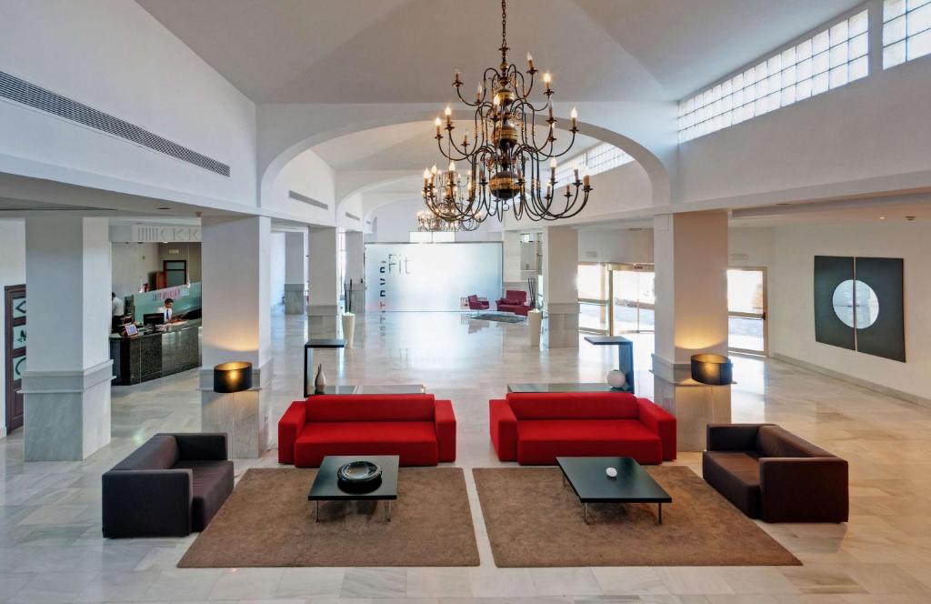 a living room with red furniture and a chandelier at Hotel Melilla Puerto, Affiliated by Meliá in Melilla