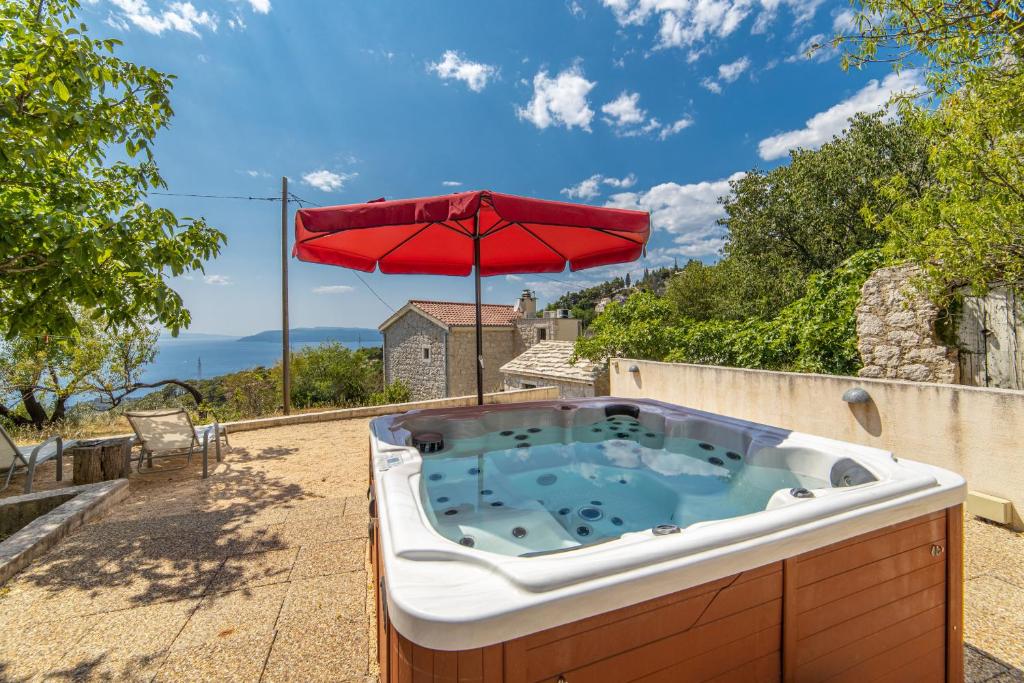 a hot tub with an umbrella on a patio at Holiday home Fetiva Makar in Makarska