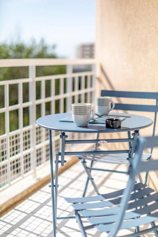 a table with two cups and two chairs on a balcony at Superbe studio avec balcon vue mer&#47;climatisation in Cagnes-sur-Mer