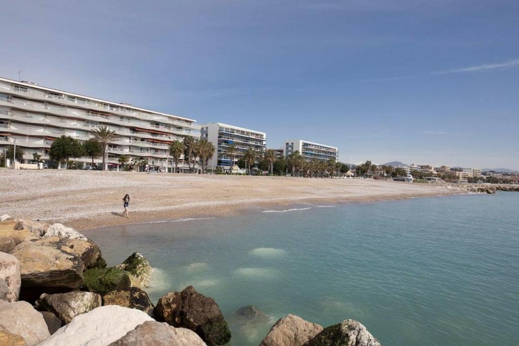 a person walking on a beach with buildings in the background at Superbe studio avec balcon vue mer&#47;climatisation in Cagnes-sur-Mer