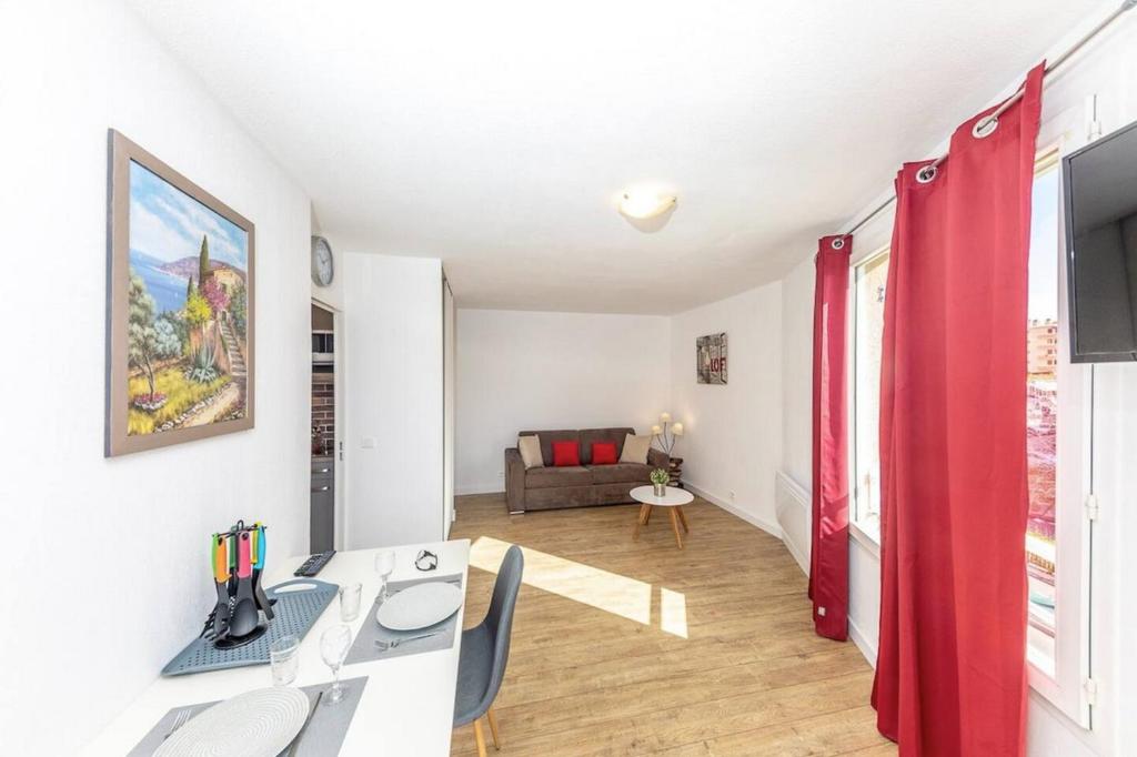 a living room with a desk and red curtains at Superbe studio avec balcon vue mer&#47;climatisation in Cagnes-sur-Mer