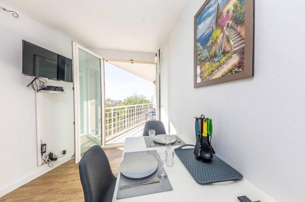 a room with a desk with chairs and a table with a computer at Superbe studio avec balcon vue mer&#47;climatisation in Cagnes-sur-Mer