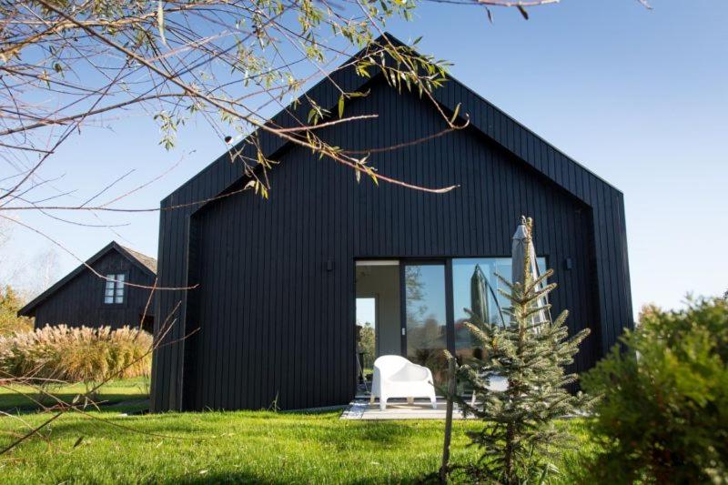 uma casa negra com uma cadeira branca à frente. em Green corner em Cracóvia