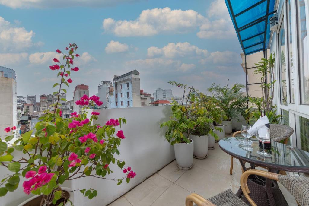 balcón con macetas y mesa de cristal en Golden Legend Diamond Hotel, en Hanói