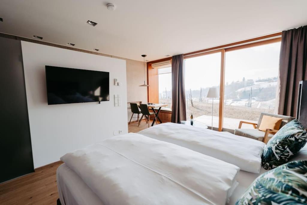 1 Schlafzimmer mit 2 weißen Betten und einem großen Fenster in der Unterkunft *Relax Apartment Hochgraßnitzberg* in den südsteirischen Weinbergen in Spielfeld