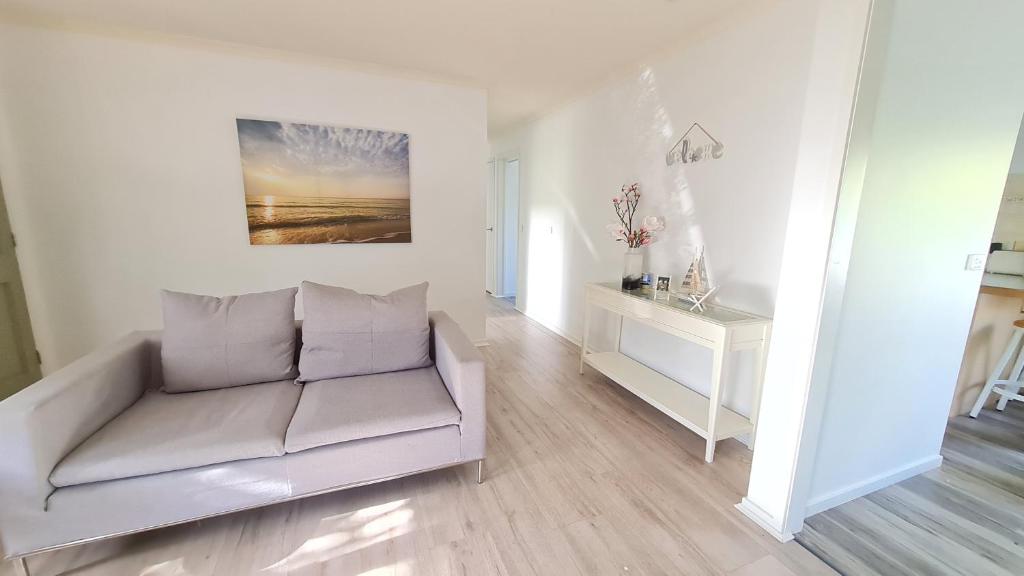 a white living room with a couch and a table at Capelsound Beach house in Capel Sound