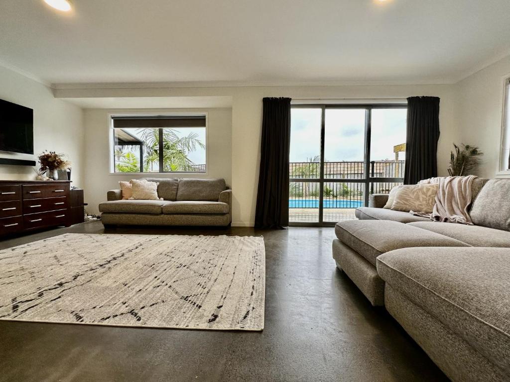 a living room with a couch and a television and a living room with a couch at Surf Stay Ahipara - 200m to the beach 2m to the pool in Ahipara