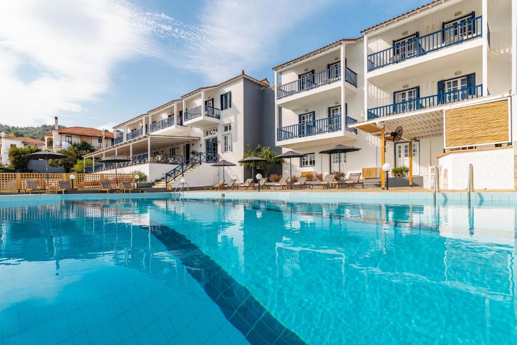 a swimming pool with blue water in front of a building at Aperitton Hotel in Skopelos Town