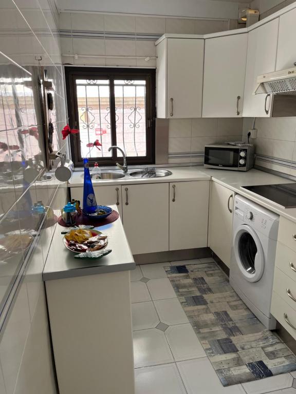 una cocina con armarios blancos y un plato de comida en una barra en CORNELIAS HOME, en Los Cristianos