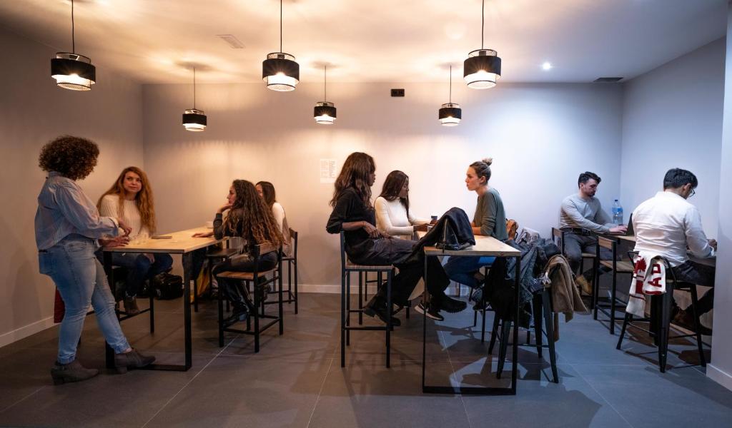 een groep mensen die aan een tafel in een kamer zitten bij Madriz Hostel in Madrid