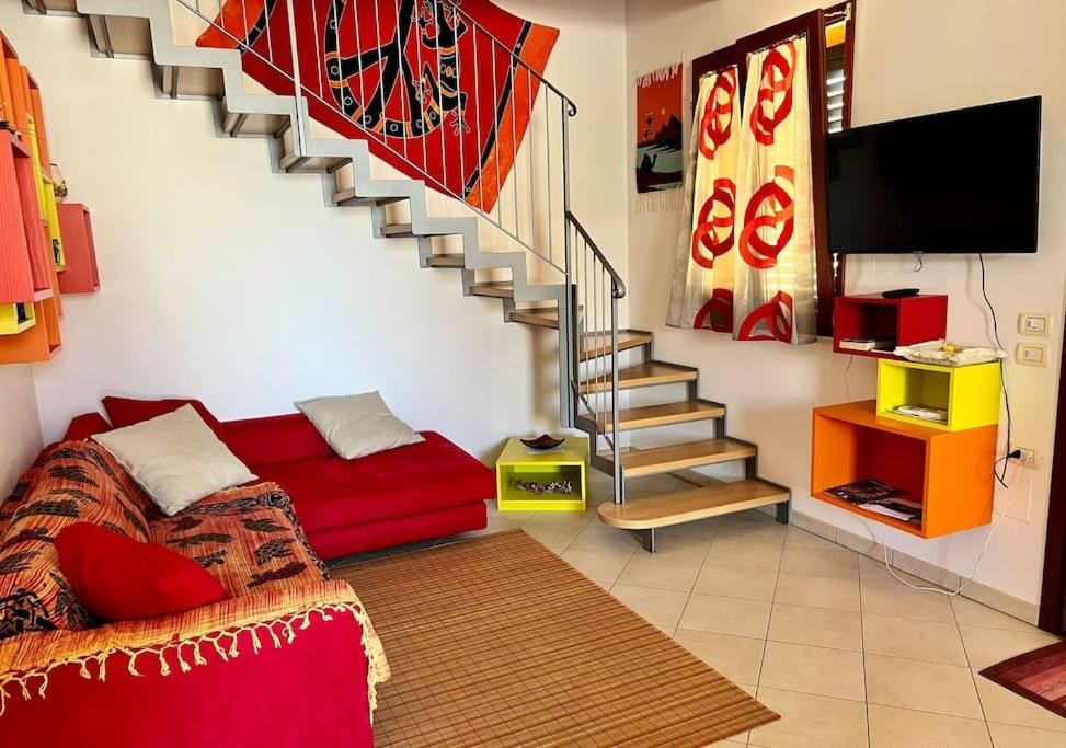 a living room with a red couch and a staircase at Casa Corinaldesi in Marotta
