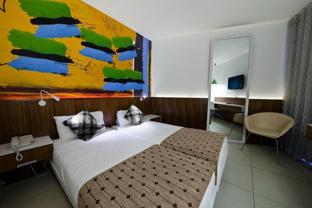 1 dormitorio con 1 cama y una pintura en la pared en Prima Vera, en Jerusalén