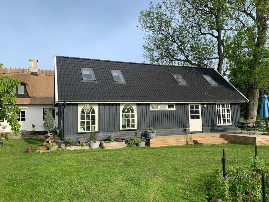 a house with a black roof and a yard at Kongsholmlund. Enjoy the countryside. in Vejby
