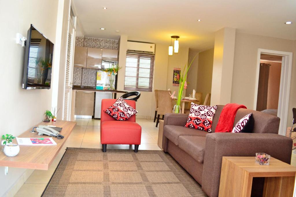 uma sala de estar com um sofá e uma cadeira vermelha em Acquah Place Residences em Acra