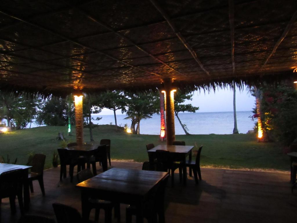 a restaurant with tables and chairs and a view of the ocean at DACOZY Beach Resort in Moalboal