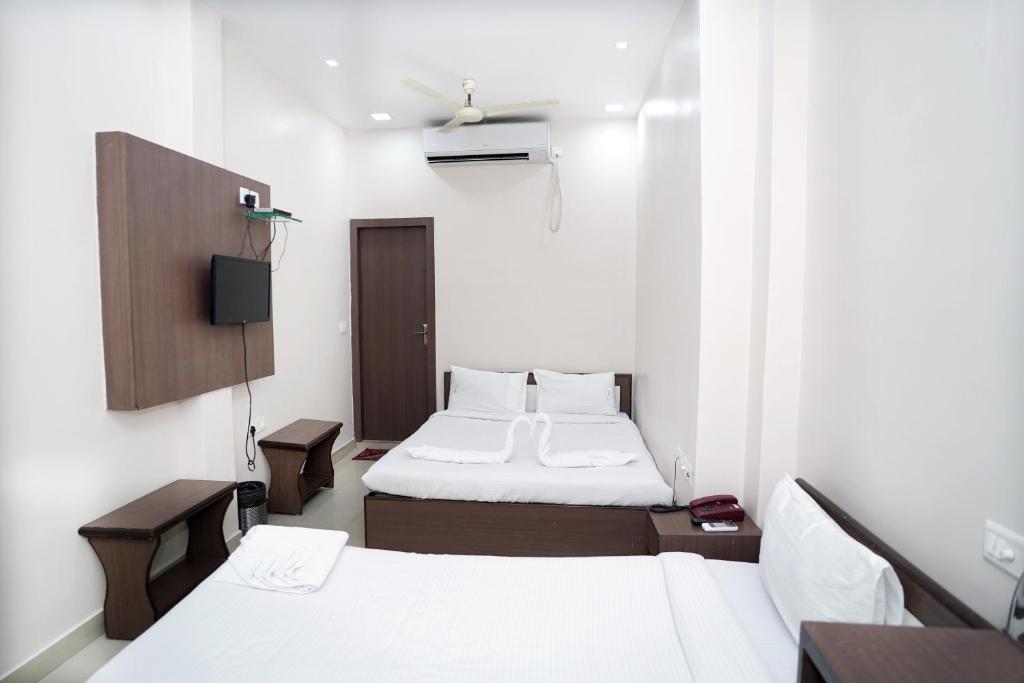 Habitación pequeña con 2 camas y TV. en Sonar Bangla Guest House, en Calcuta