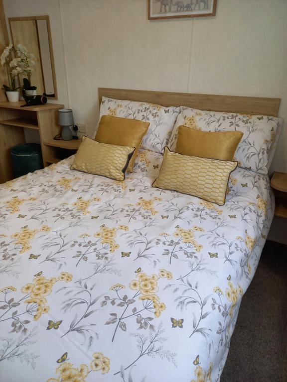 a bed with yellow flowers on it with two pillows at Lindens on the Lido in Knaresborough