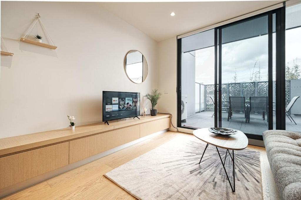 ein Wohnzimmer mit einem Sofa und einem TV in der Unterkunft Richmond New 1br1ba Free Park Outdoor Bbq in Melbourne